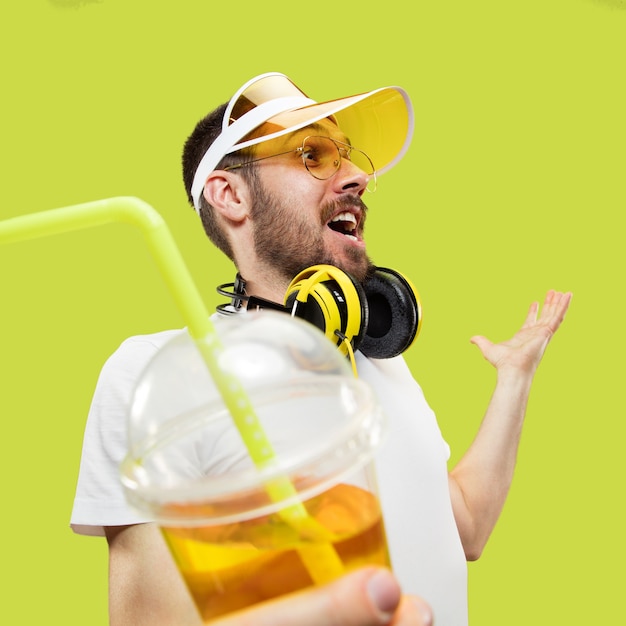 Happy meeting. Half-length close up portrait of young man in shirt. Male model with headphones and drink. The human emotions, facial expression, summer, weekend concept.