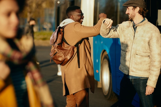 Free photo happy men elbow bumping while greeting at bus station