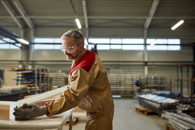 Бесплатное фото Счастливый плотник среднего возраста, работающий в своей мастерской