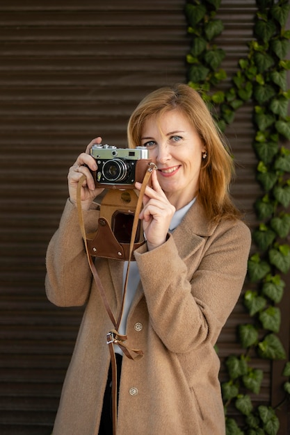 Free photo happy middle aged woman holding a camera