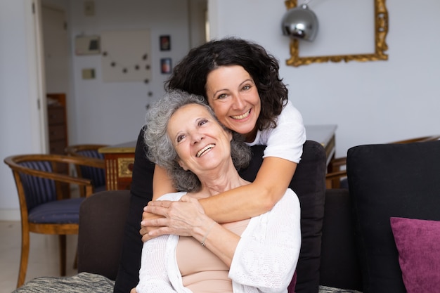 Happy middle aged woman hugging senior lady