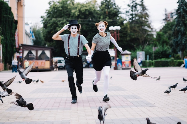 Happy mime couple running on pavement