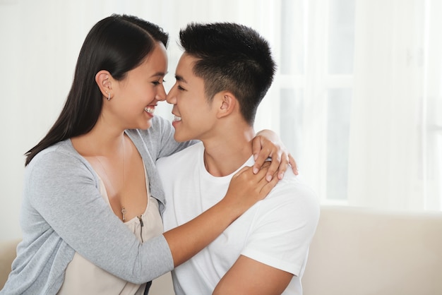 Happy mixed race couple hugging on couch