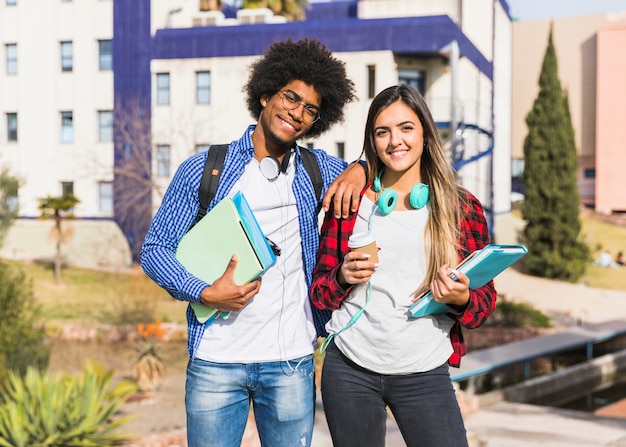 Happy mixed race couple posing in front of university building