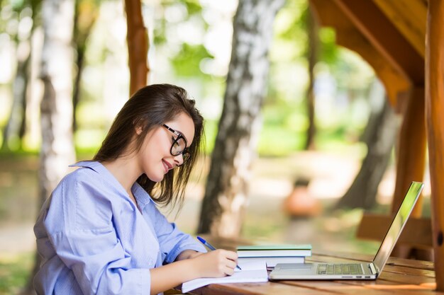 Happy model using a laptop in a park table in the morning