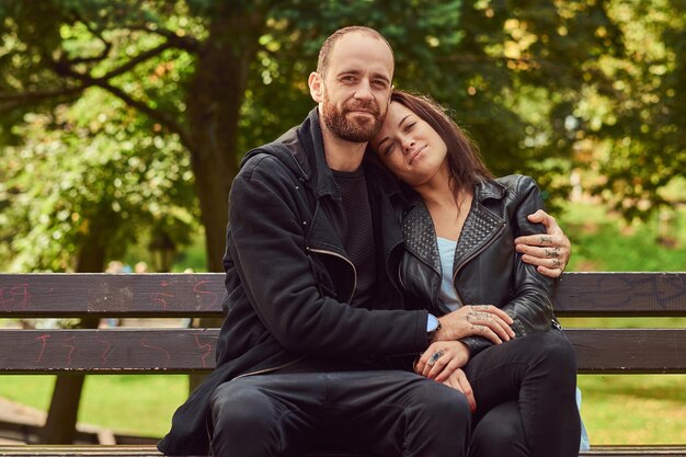 Счастливая современная пара обнимается на скамейке в парке. Наслаждаясь их любовью и природой.