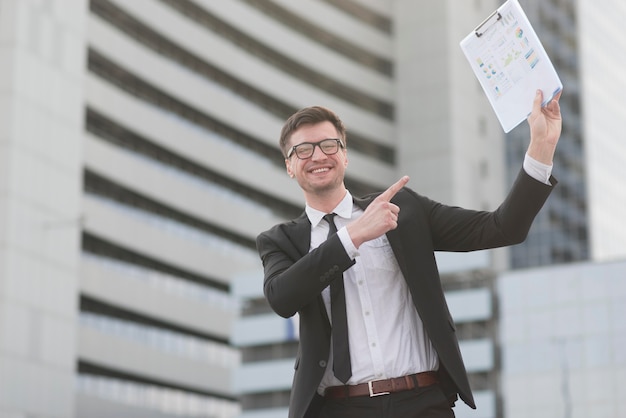 Happy modern man pointing at clipboard