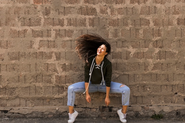 Free photo happy modern style female dancer posing in front of wall