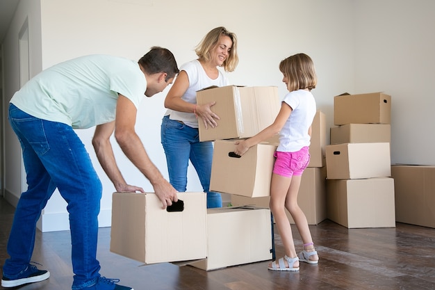 Бесплатное фото Счастливая мама, папа и ребенок держат картонные коробки и переезжают в новый дом или квартиру