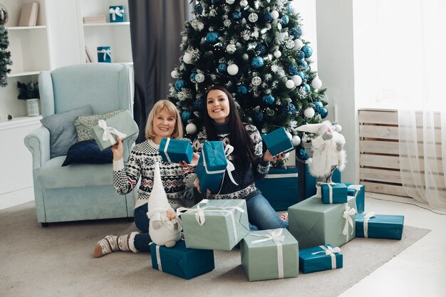 Happy mom and daughter unpack Christmas gifts