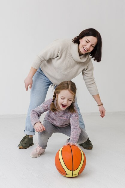 Happy mom and girl playing basketball