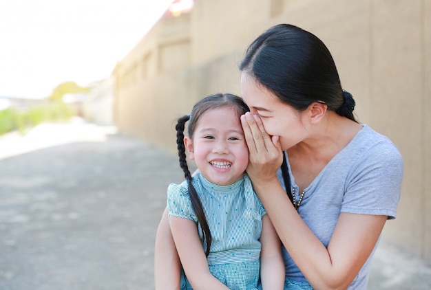 Premium Photo | Happy mom whispering a something secret to her little  daughter ear.