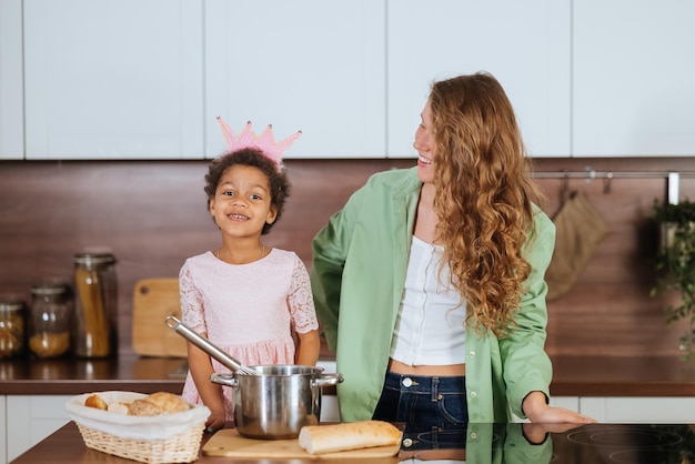 Happy mommy and daughter girl having fun while cooking in kitchen