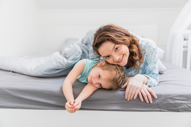 Бесплатное фото Счастливая мать и дочь, лежа на кровати