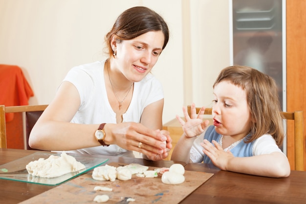 Happy mother and baby  sculpting from clay at table