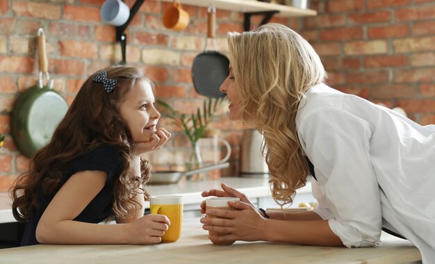 Happy mother and daughter having breakfast in the kitchen