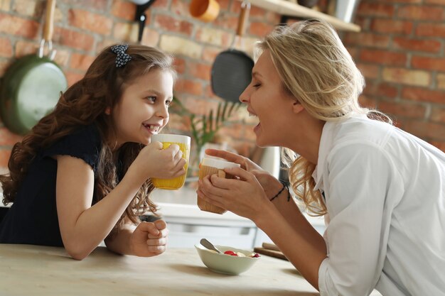 Happy mother and daughter having breakfast in the kitchen