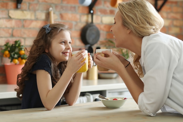 Madre e figlia felici che mangiano prima colazione nella cucina