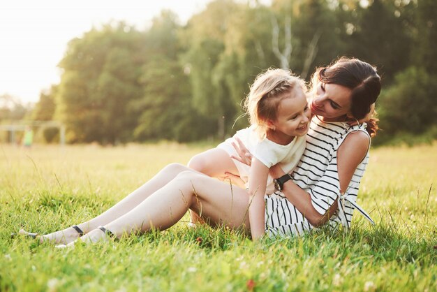 Happy mother and daughter hugging in a park in the sun on a bright summer of herbs.