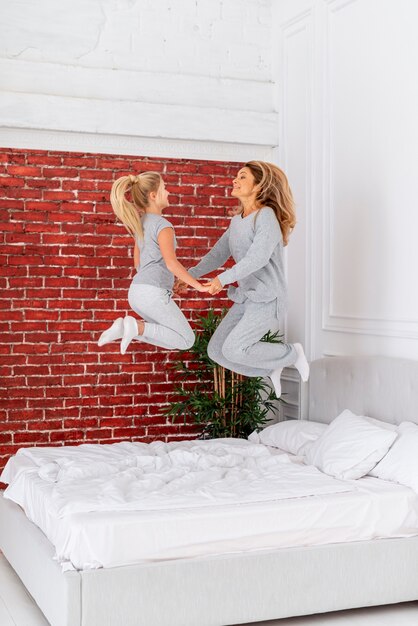 Happy mother and daughter jumping in bed