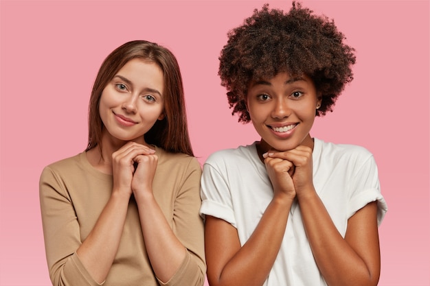 Happy mother and daughter keep hands together under chin