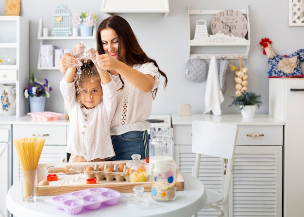 Happy mother and daughter playing with flour