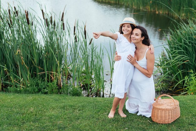 幸せな母と娘、湖のそばでポーズ