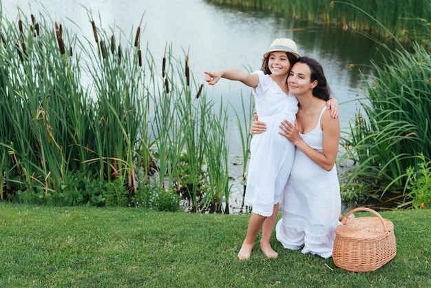 Счастливая мать и дочь позирует на берегу озера