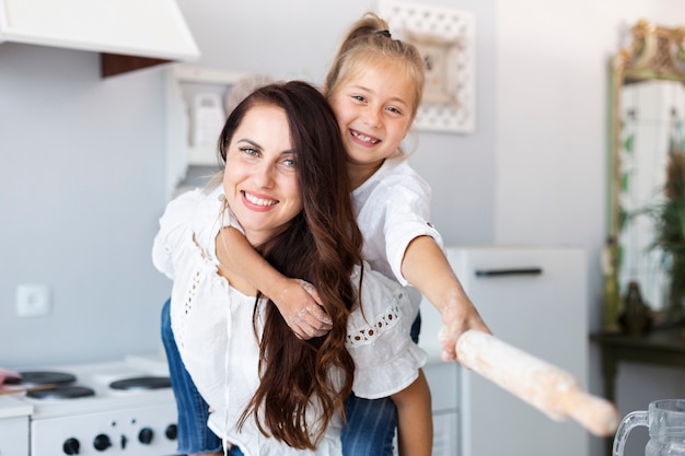 Happy mother and daughter posing with kitchen roller