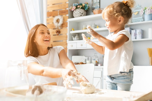 Happy mother and daughter preparing dough