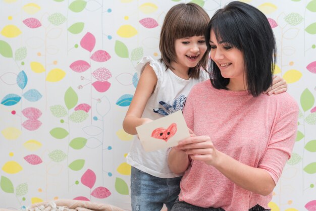 Happy mother and daughter reading greeting card