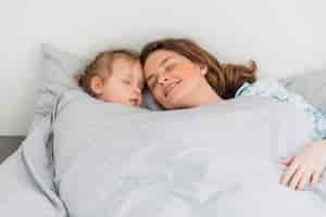 Foto gratuita madre felice e figlia che dormono insieme nella casa