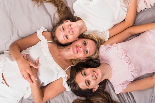Happy mother and daughters lying on bed 