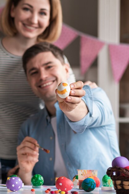 幸せな母と父はイースターの塗装卵を表示