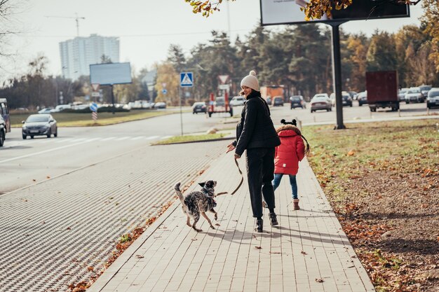 행복 한 어머니와 그녀의 딸 거리에서 강아지와 함께 산책.