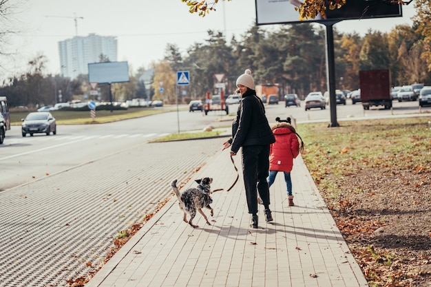 Happy mother and her daughter walk with dog at the street.