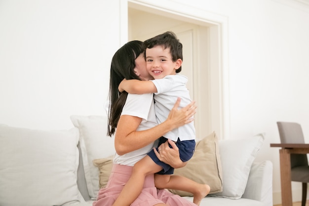 Счастливая мать обнимает и целует своего маленького сына с любовью.
