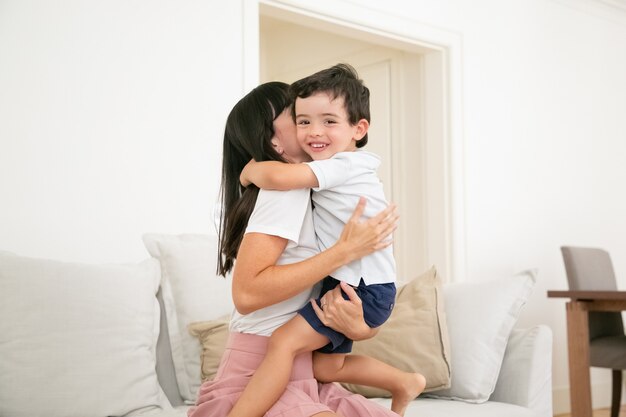 Happy mother hugging and kissing her little son with love.