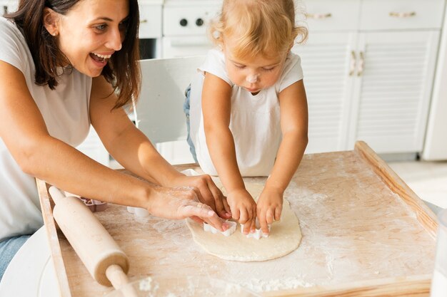 Happy mother and little girl preparing cookies