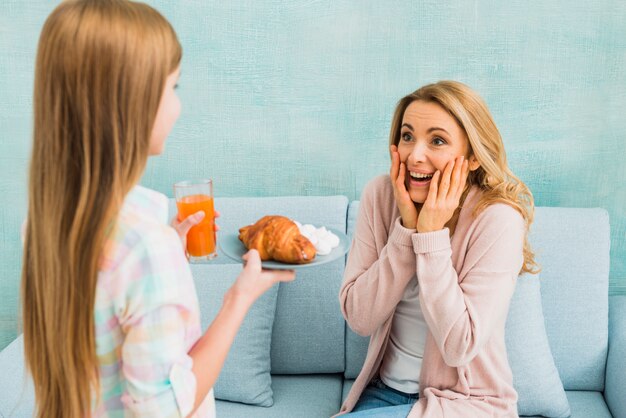 Happy mother looking at daughter with breakfast