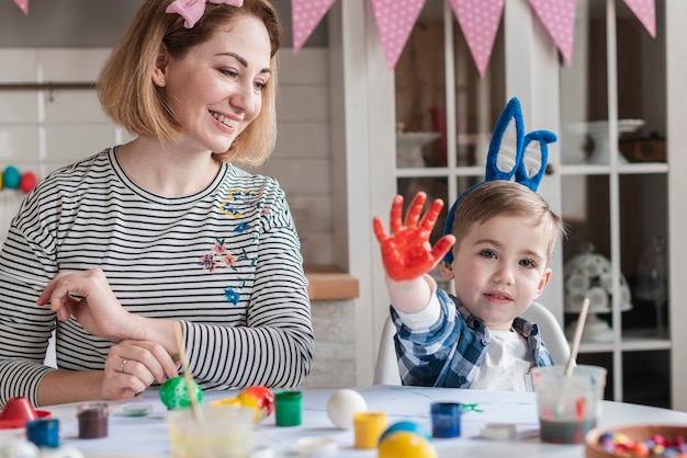 Happy mother painting easter eggs with son