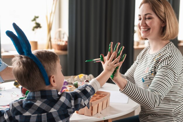 Happy mother painting sons hands for easter