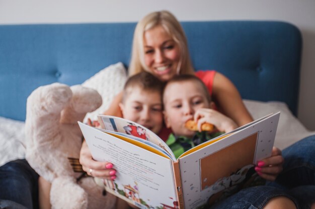 Счастливая мать читает книгу с детьми