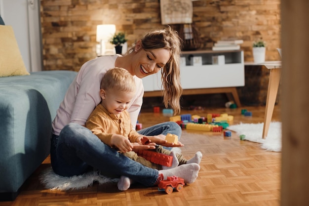 happy mother and son playing with toy blocks in the living room