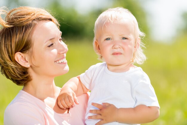 Happy mother and toddler son in the spring meadow outdoor portrait