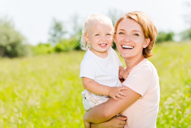 Happy mother and toddler son in the spring meadow outdoor portrait