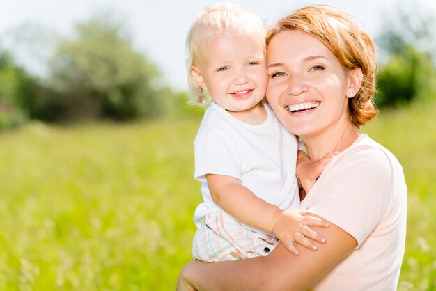 Happy mother and toddler son in the spring meadow outdoor portrait