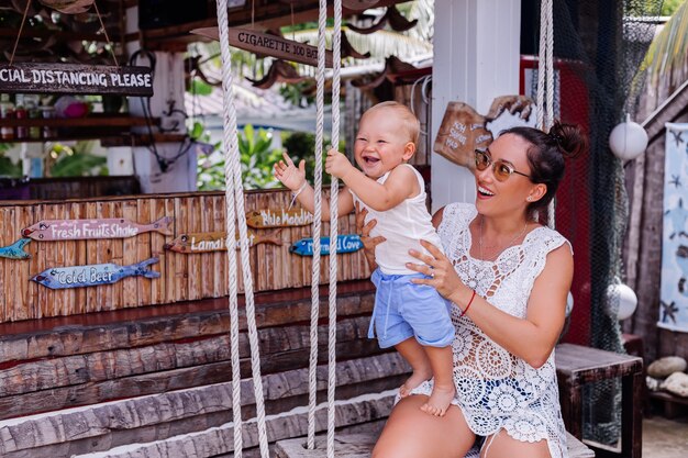 Happy mother with baby boy on swing