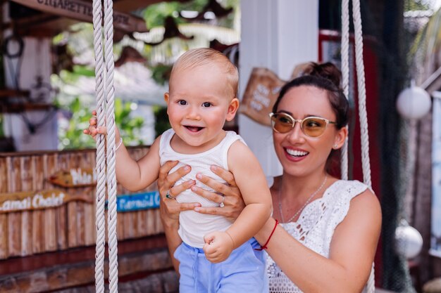 Happy mother with baby boy on swing