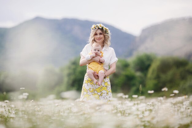 happy mother with cute baby newborn outdoor in camomile field